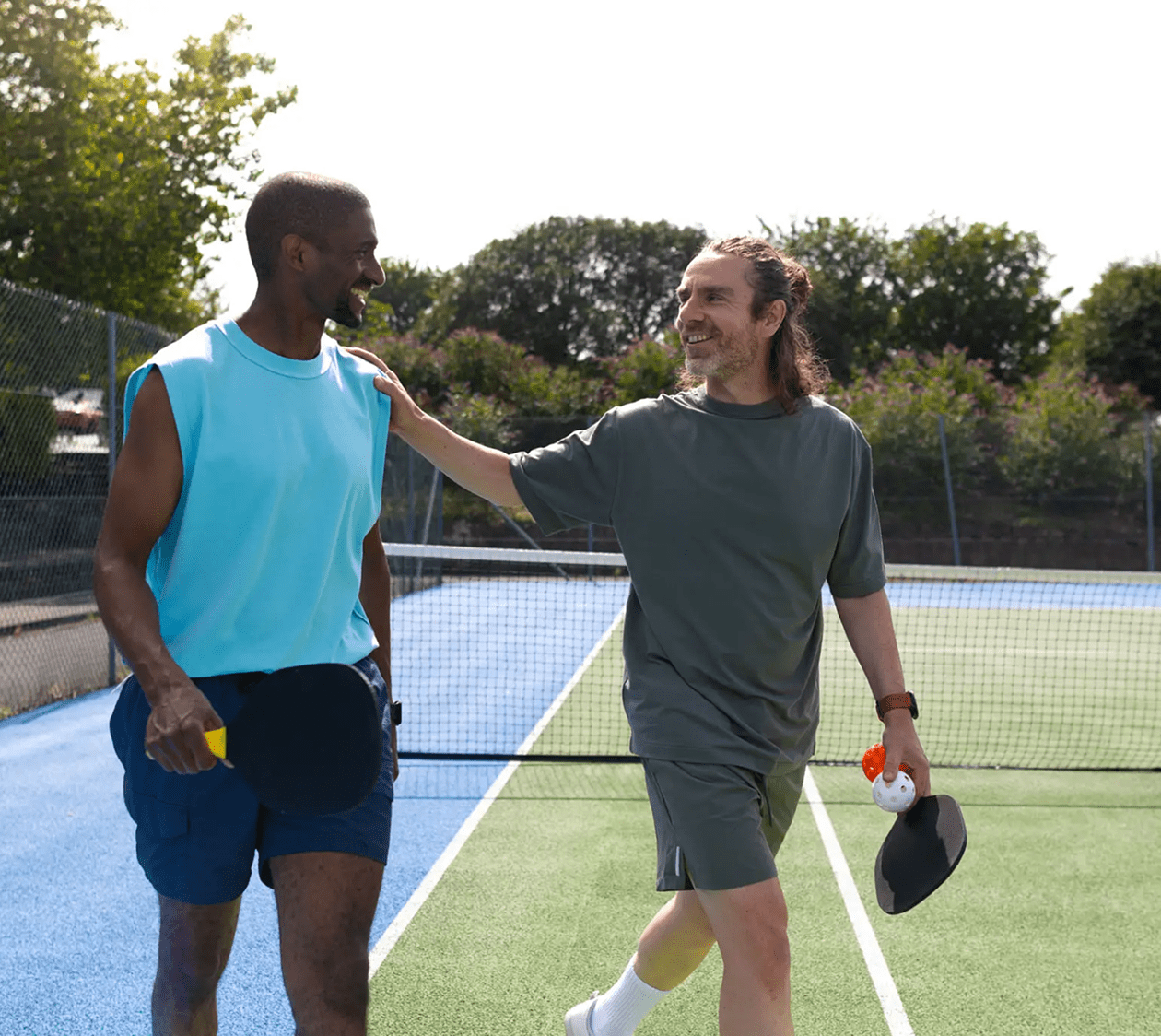 Two men with tennis paddles smiling